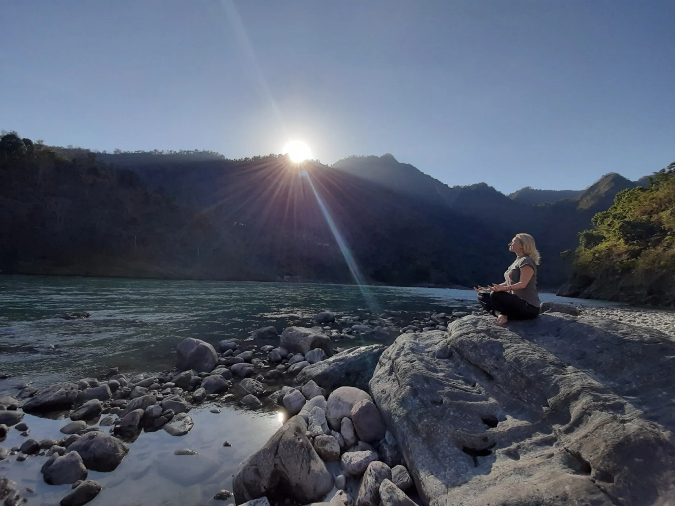 Tatiana meditating beside a mountain river